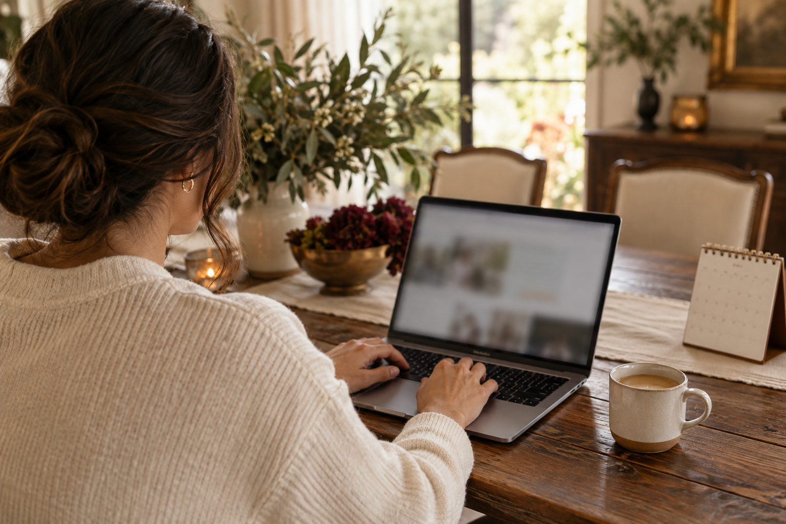 A person using a laptop beside a calendar to plan an event